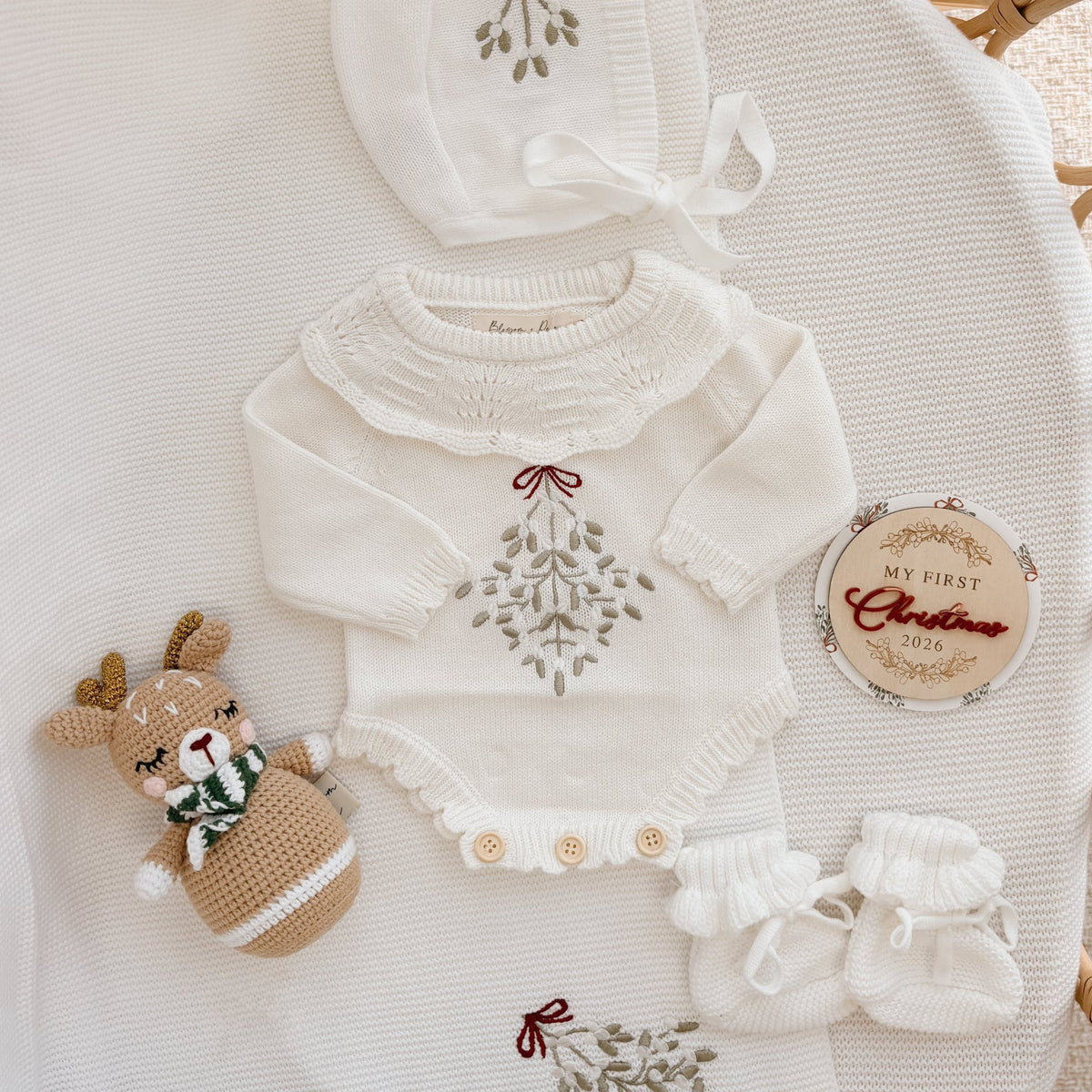 Mistletoe embroidered knit baby romper with a pointelle yoke, bonnet, booties and crochet reindeer rattle