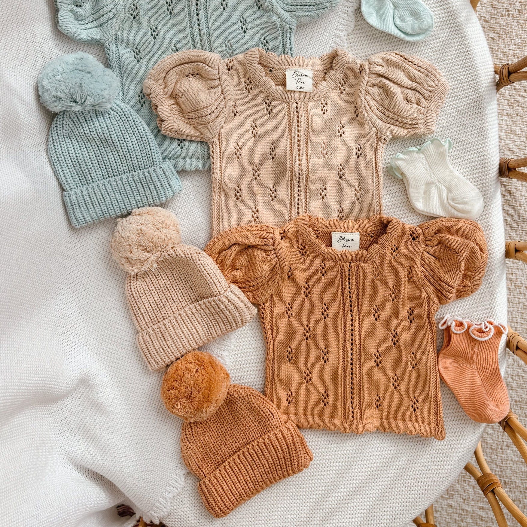 Margot pointelle knit baby rompers in Periwinkle Blue, Vanilla Oat and Pumpkin styled with pom beanies and socks