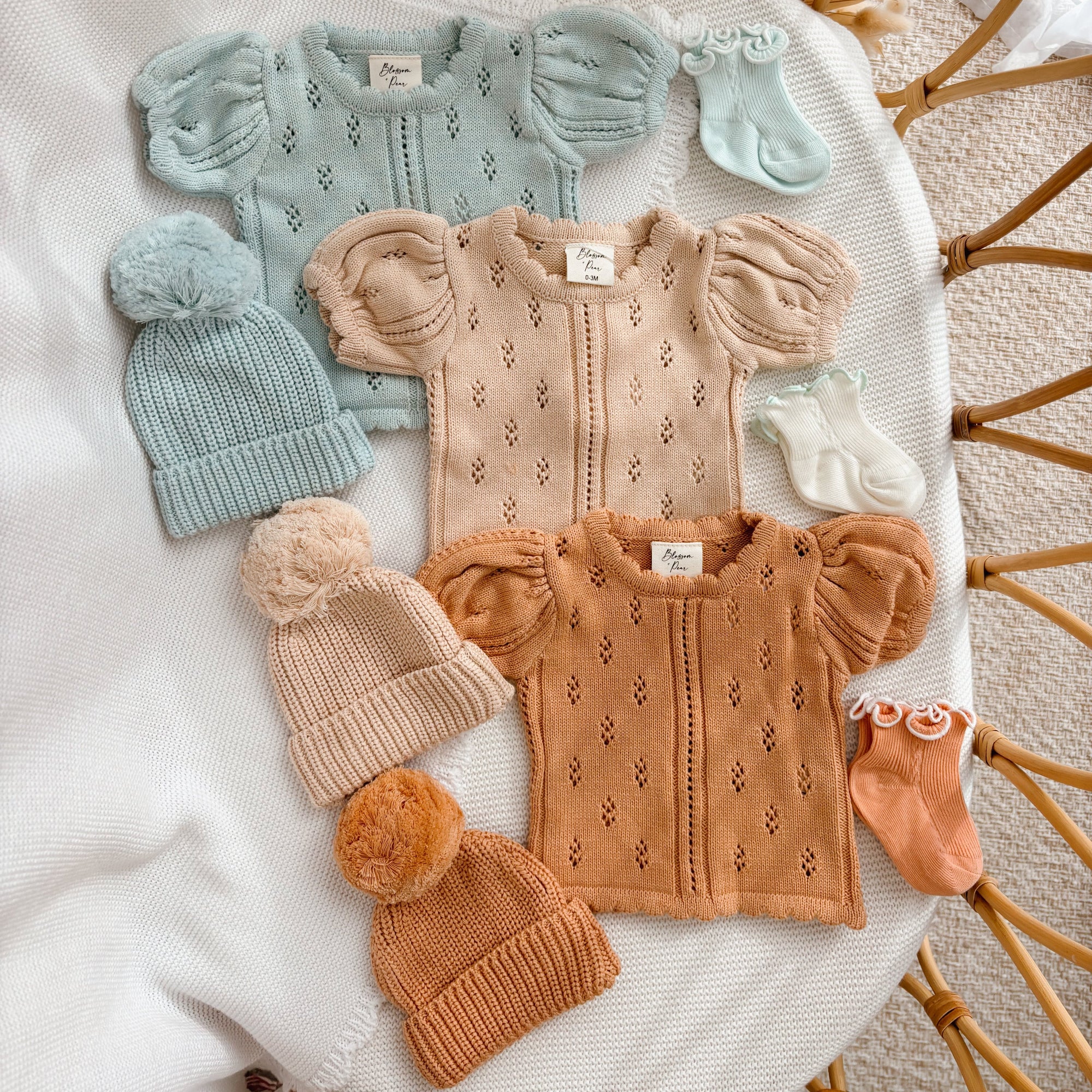 Margot pointelle knit baby rompers in Periwinkle Blue, Vanilla Oat and Pumpkin with matching pom beanies and socks