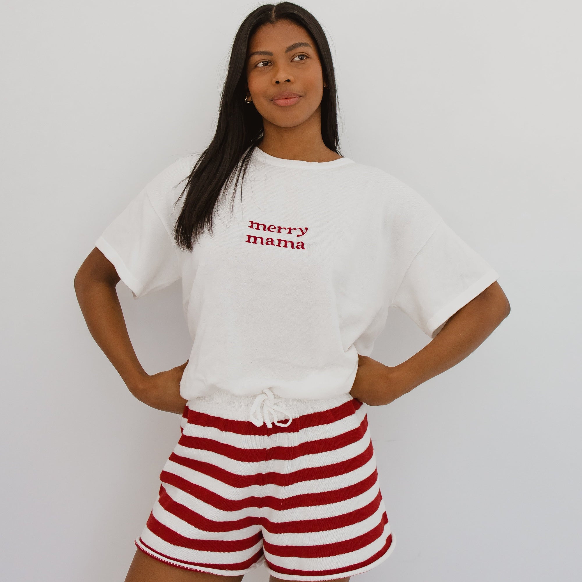 Woman in a merry mama embroidered white tee and red stripe knit shorts