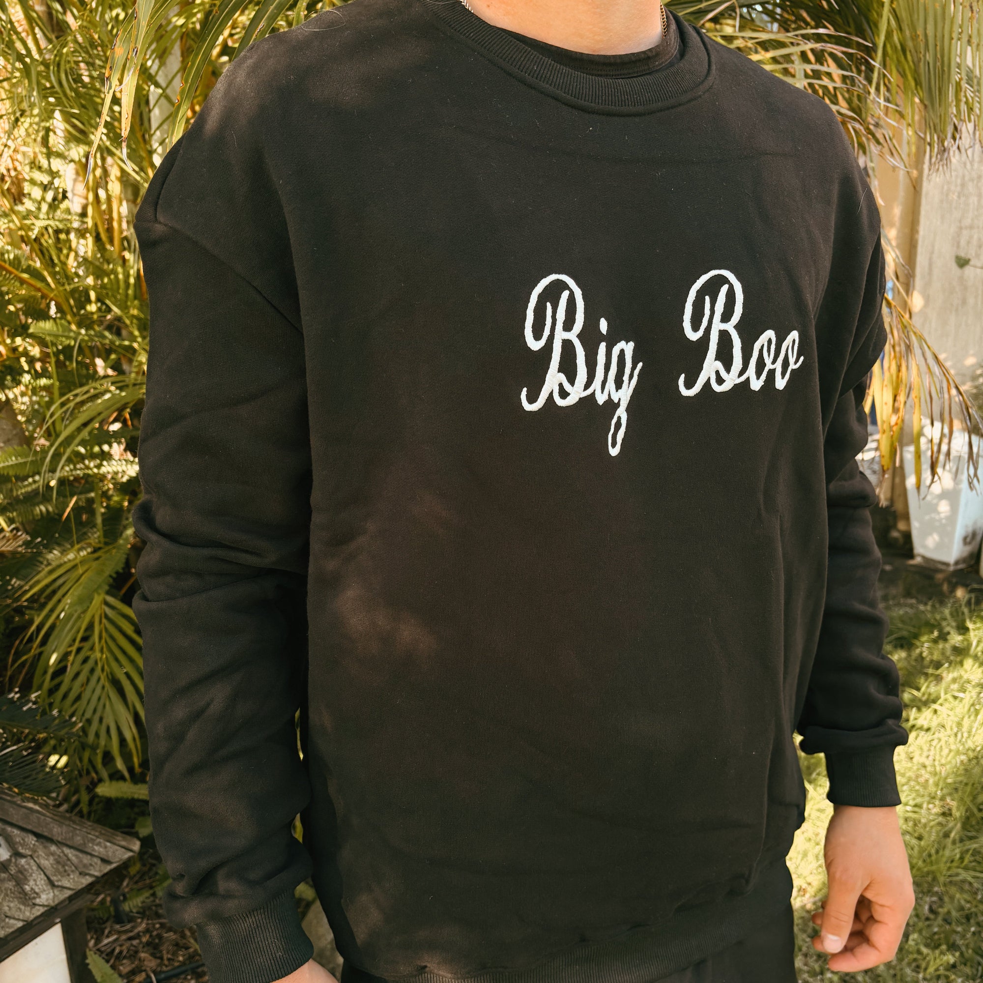 Close up of a black crew sweatshirt embroidered with Big Boo in white script