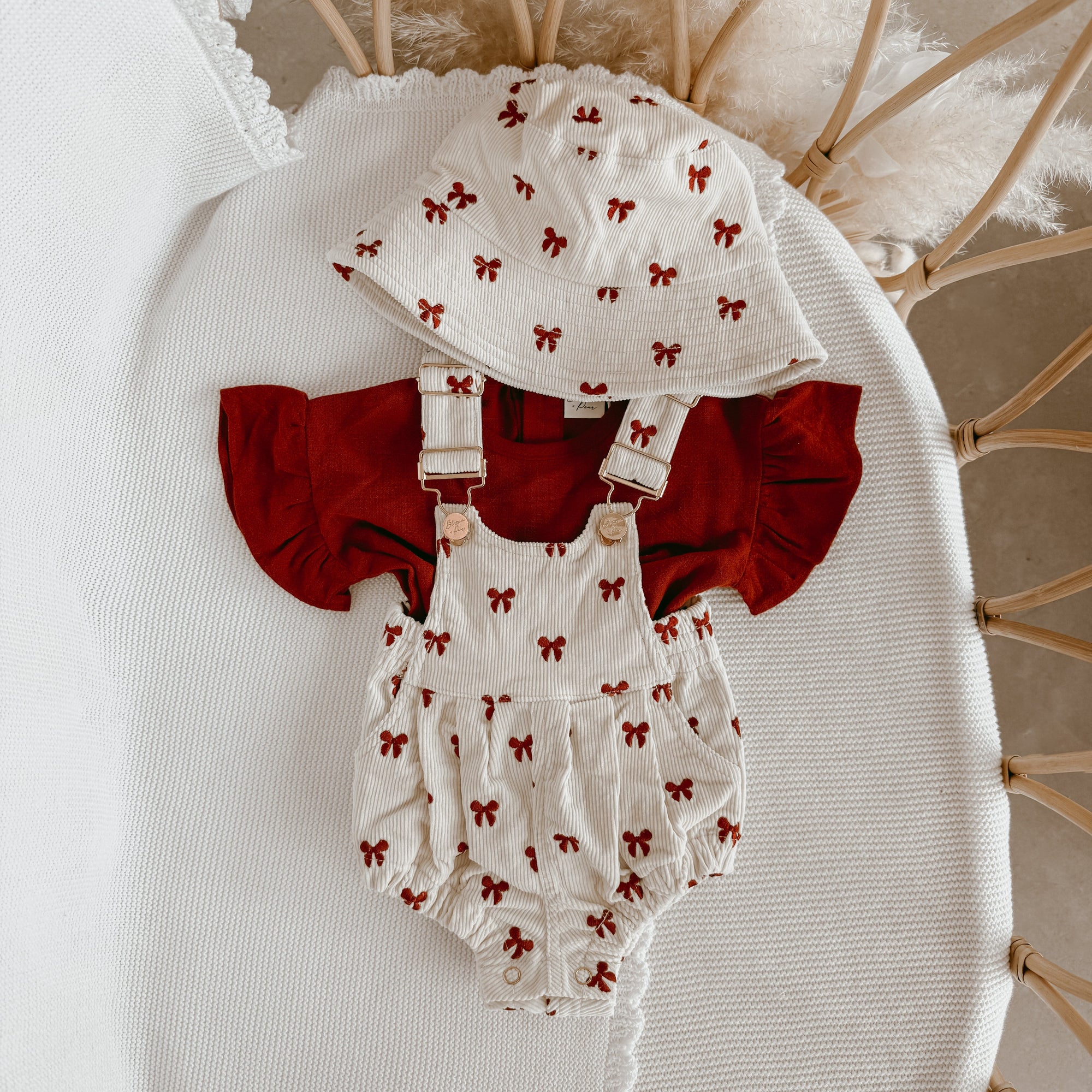 Cream corduroy baby overall romper with a red bow print, matching bucket hat and red flutter sleeve tee