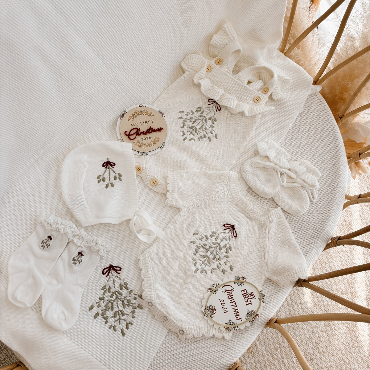 My First Christmas mistletoe embroidered baby set flat lay with romper, bonnet, socks, booties and keepsake discs