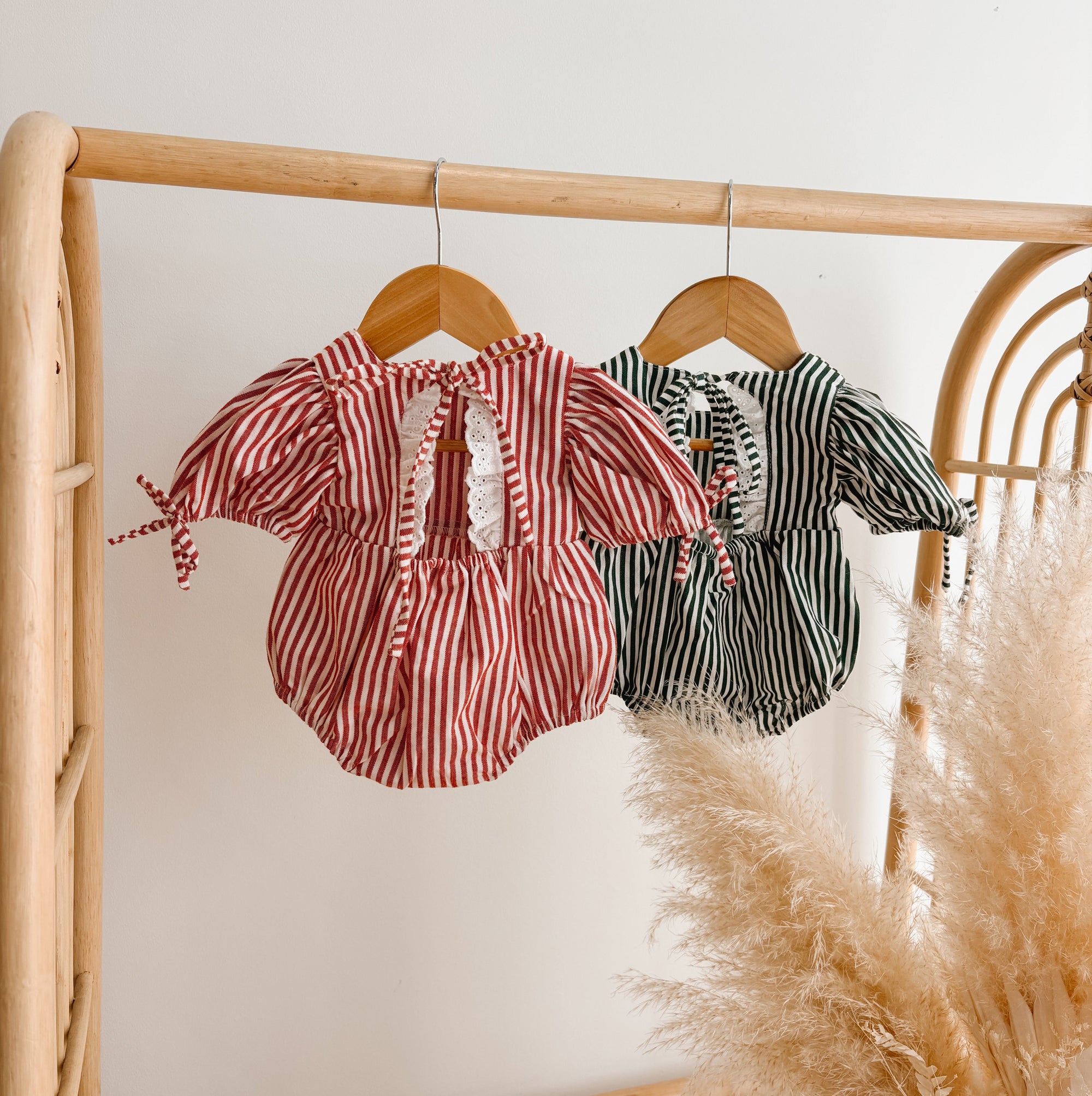 Back view of red stripe and green stripe baby rompers showing broderie trim and tie detail