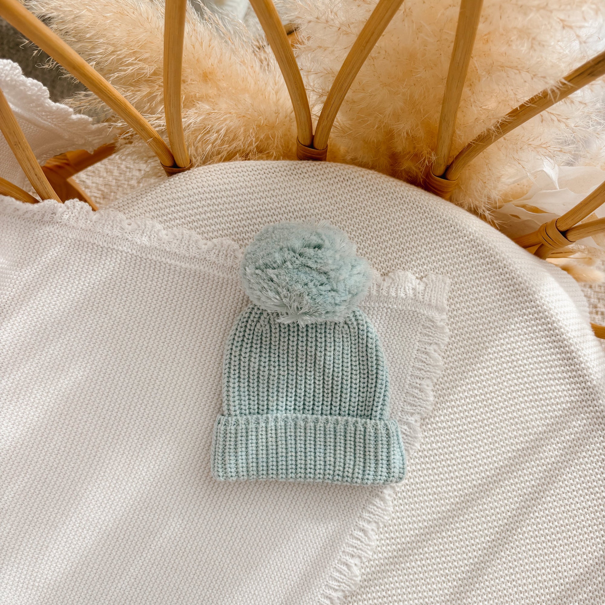 Periwinkle Blue chunky knit baby pom beanie on a cream knit blanket