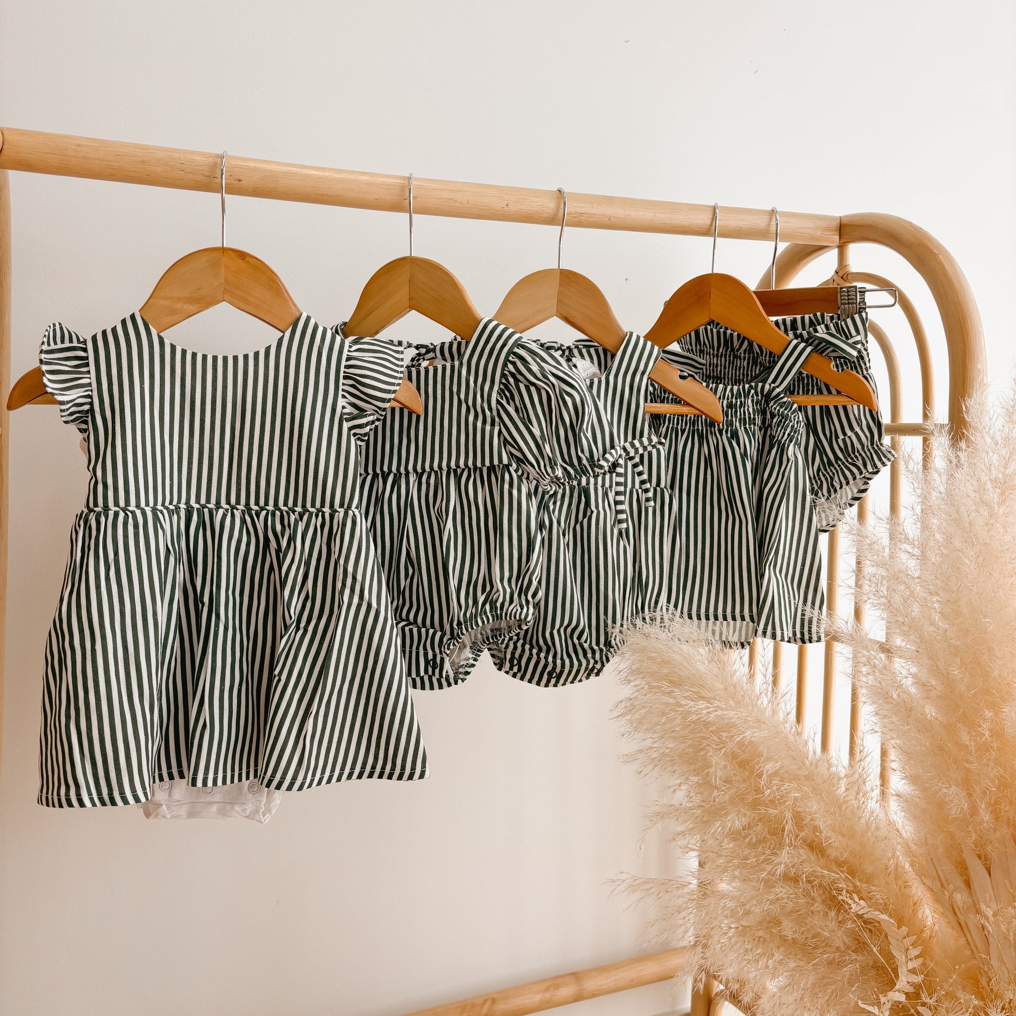 Green stripe Christmas dresses, rompers and bloomer sets hanging on a rattan clothes rail