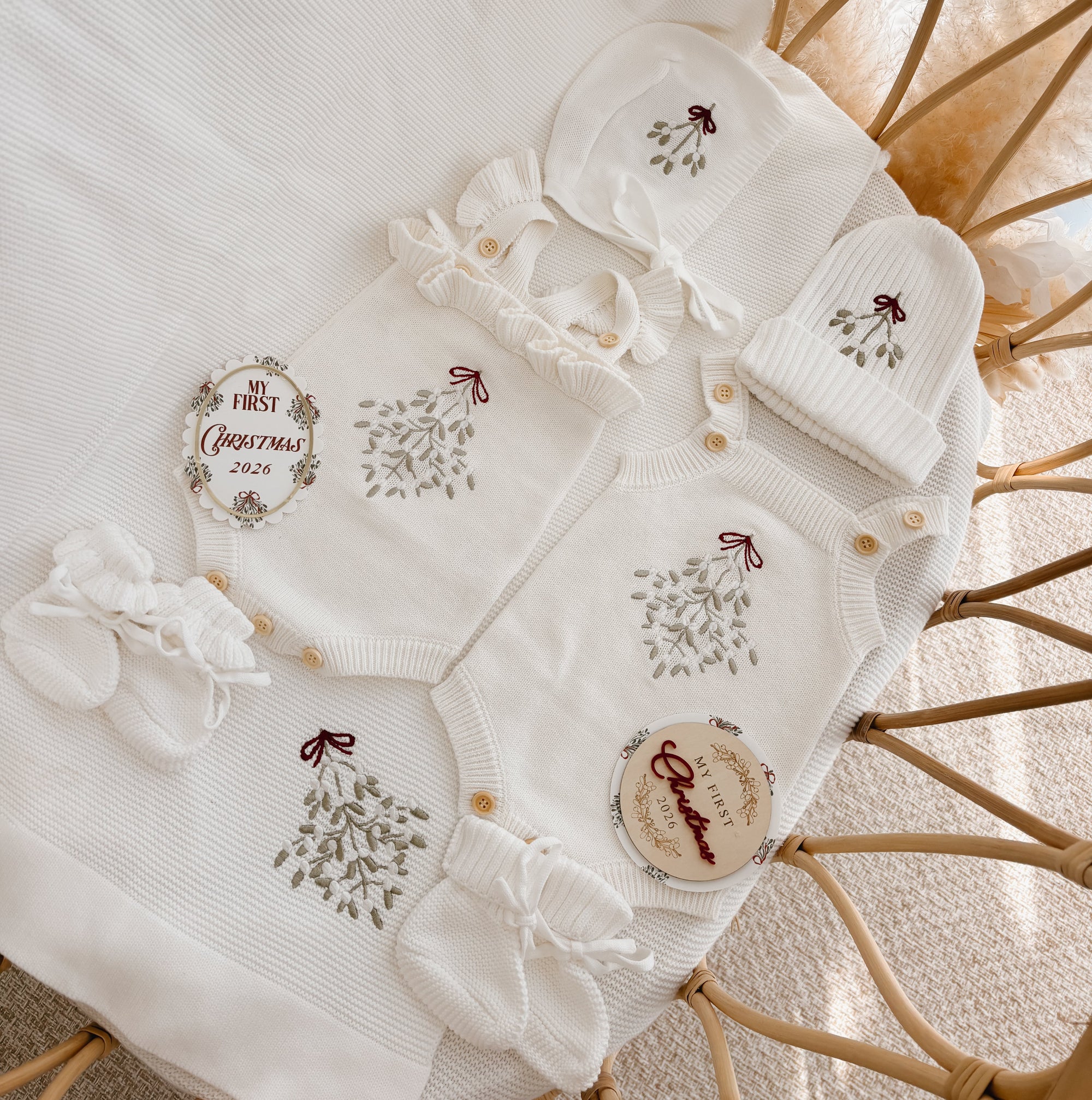 Two mistletoe embroidered knit baby rompers with bonnet, beanie, booties and milestone discs