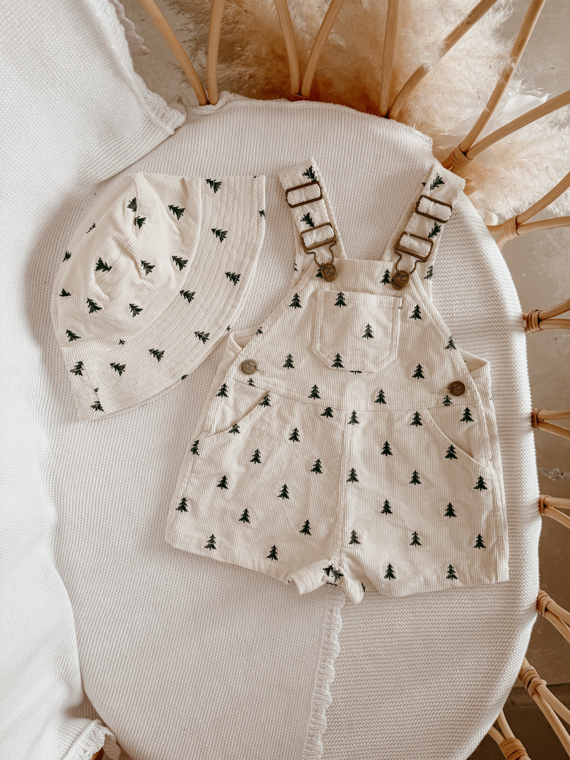 Cream corduroy kids overalls with a green Christmas tree print and matching bucket hat