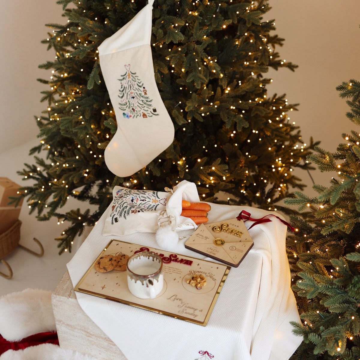 Mini linen Santa sack with carrots and a plate of treats for Santa beneath a linen Christmas stocking hanging on the tree
