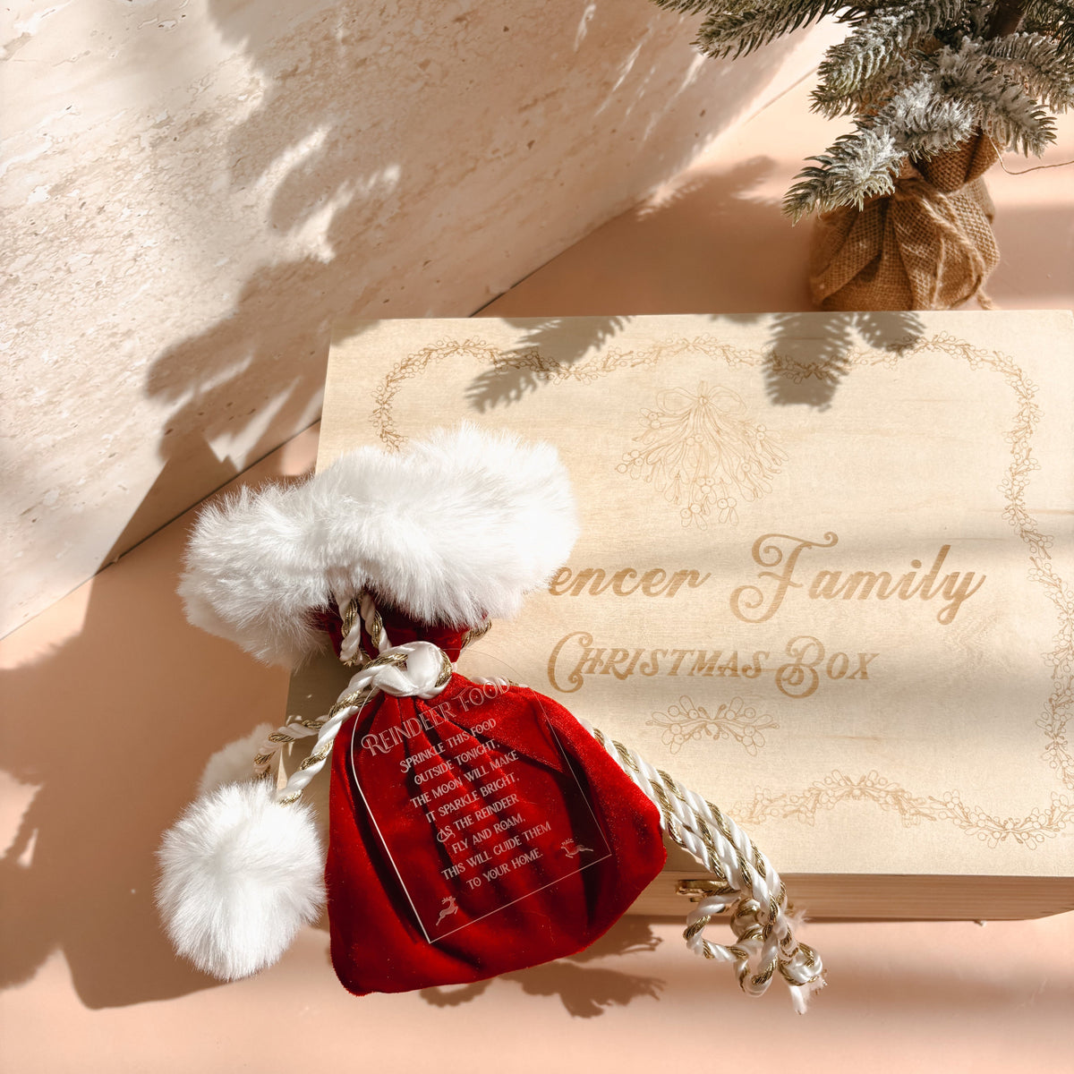 A personalized Christmas mystery box for the 'Spencer Family' shown with its kraft paper packaging and a red velvet Santa pouch filled with mystery items, styled on a warm beige surface with soft shadows.