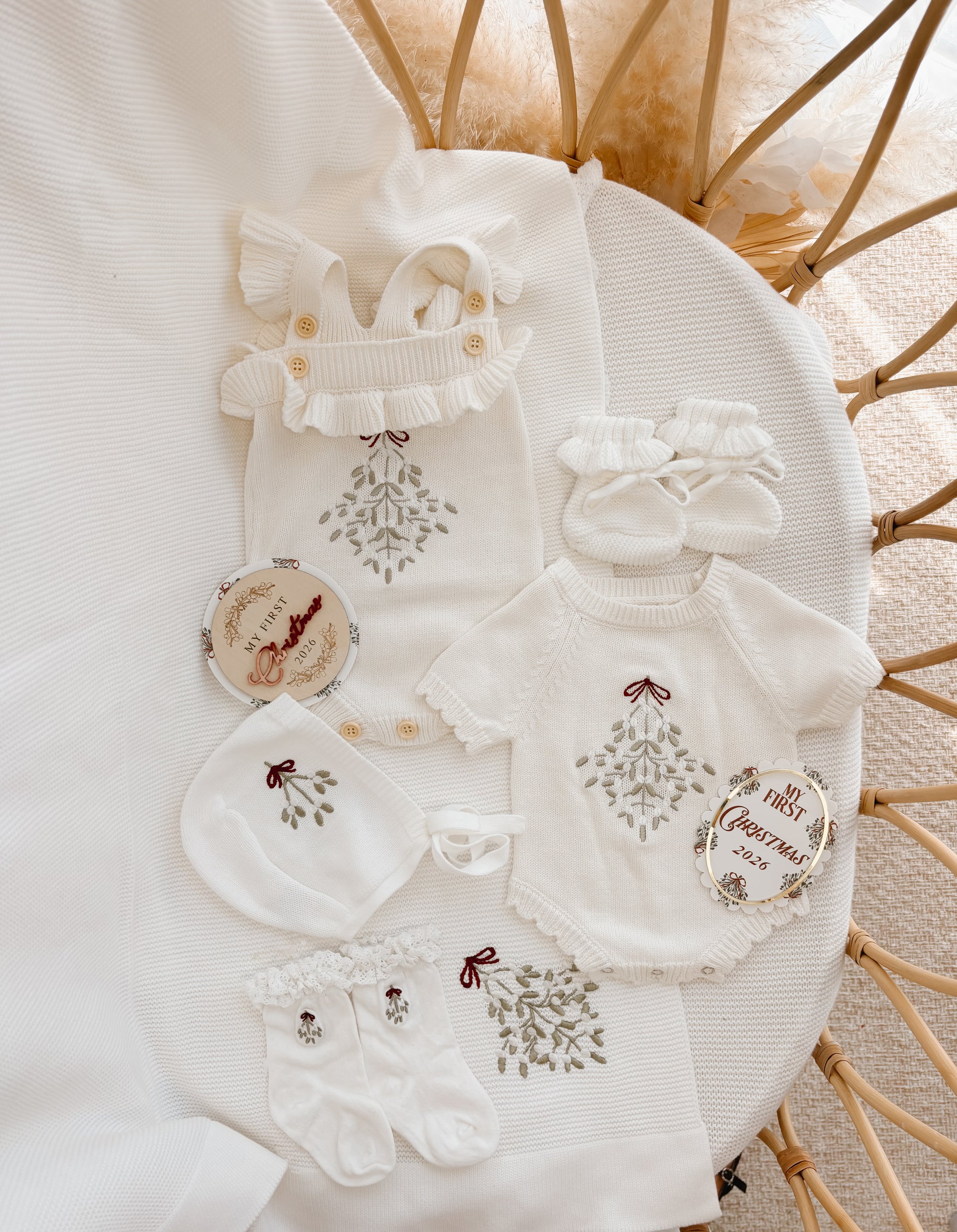 Two mistletoe embroidered knit baby rompers with bonnet, booties, socks and My First Christmas 2026 discs