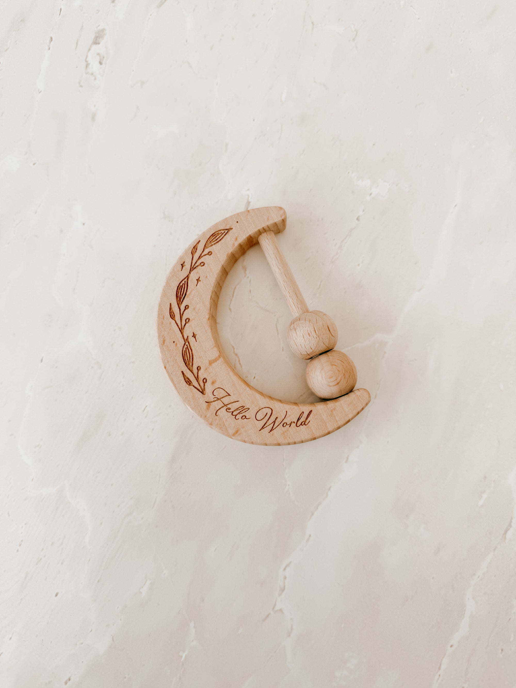 Wooden baby rattle with 'Hello World' engraving on a light background