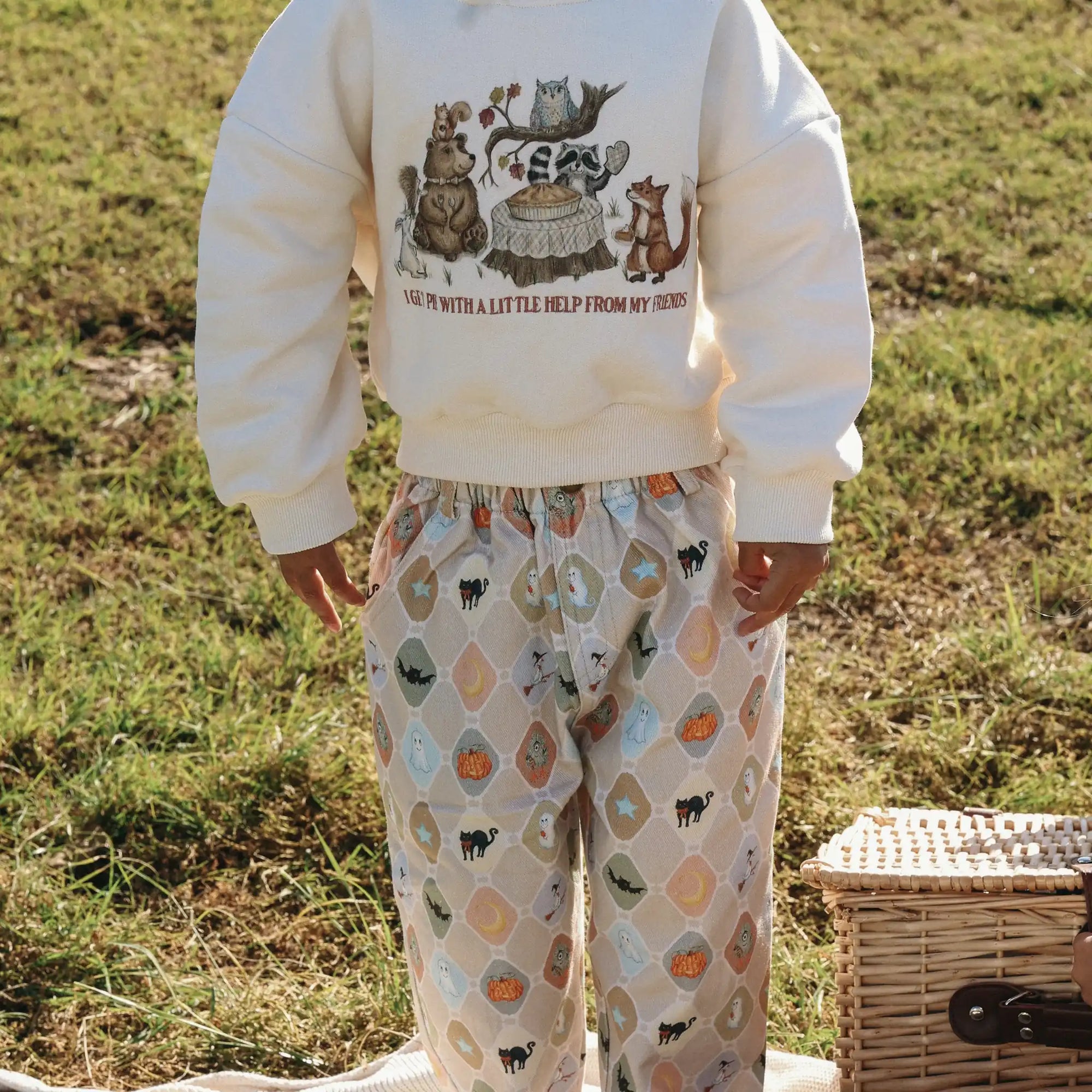Back view of a cream sweatshirt printed with woodland animals worn with Halloween print pants