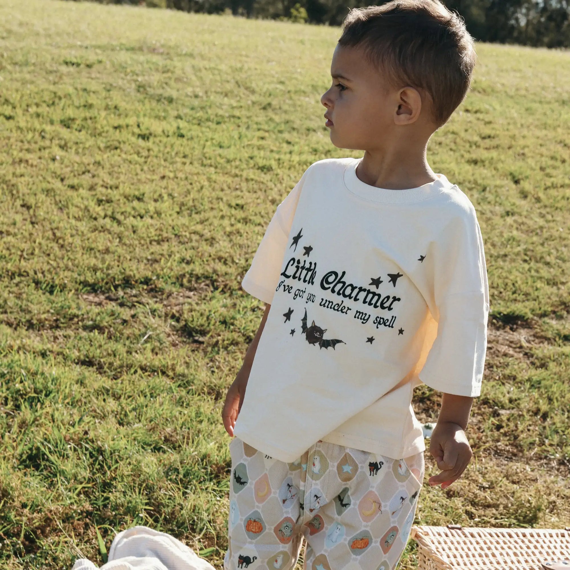 Toddler standing in a Little Charmer tee with bat and star print and matching Halloween print pants