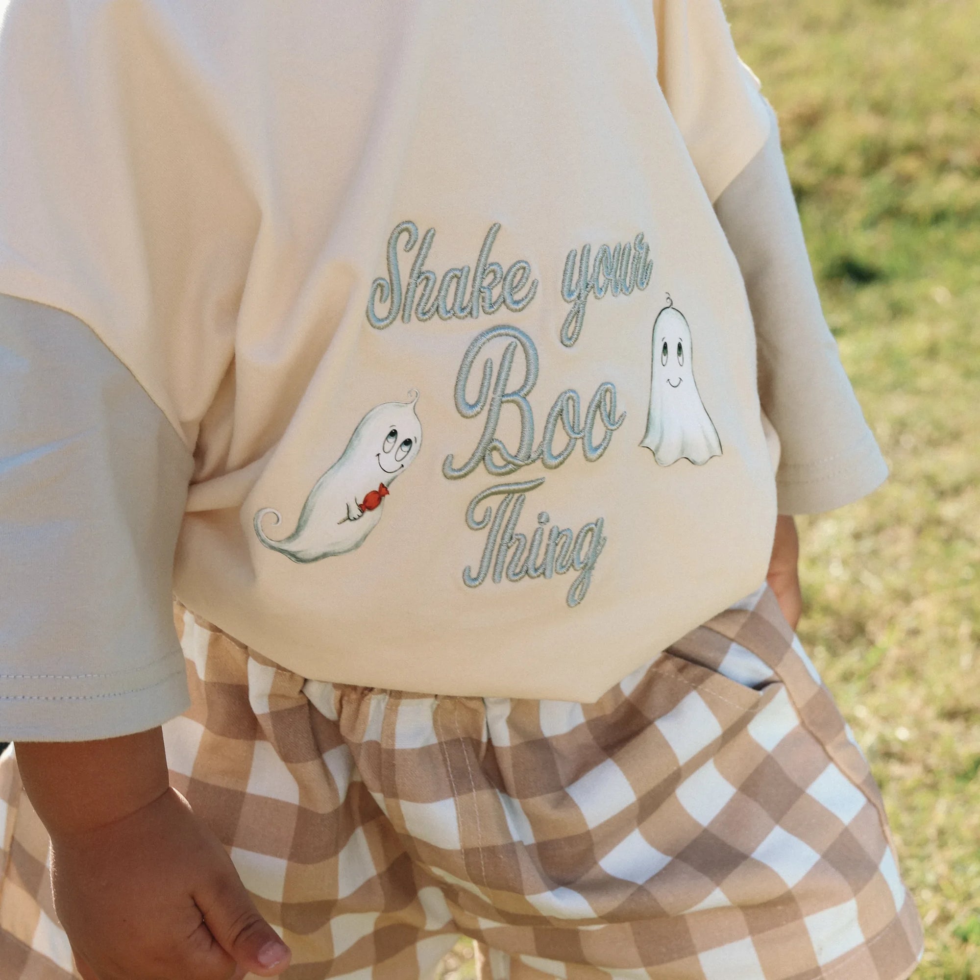 Detail of the Shake Your Boo Thing ghost print on a cream tee with tan gingham paperbag shorts