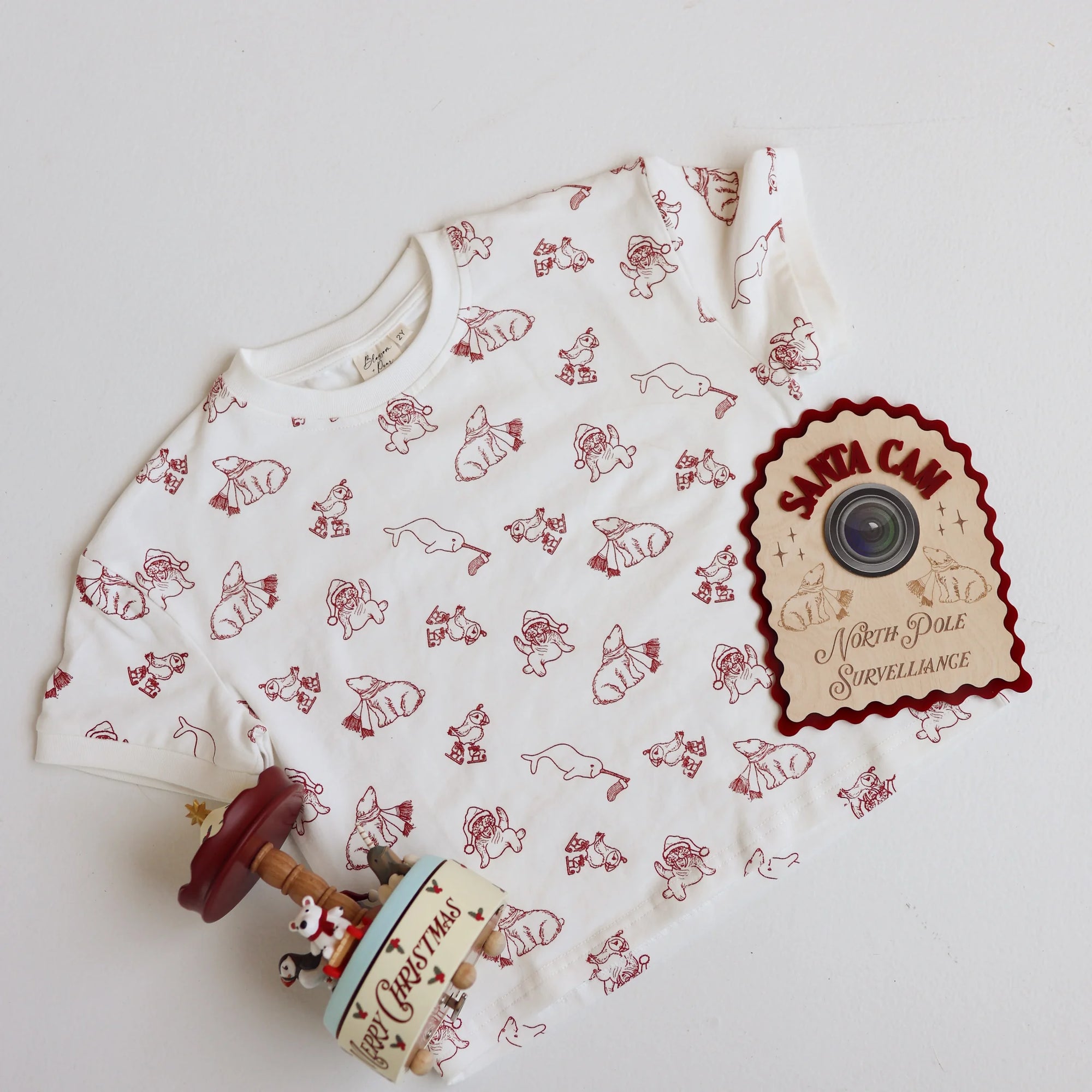 Christmas bear print shirt flat lay with a Santa Cam North Pole surveillance sign and music box