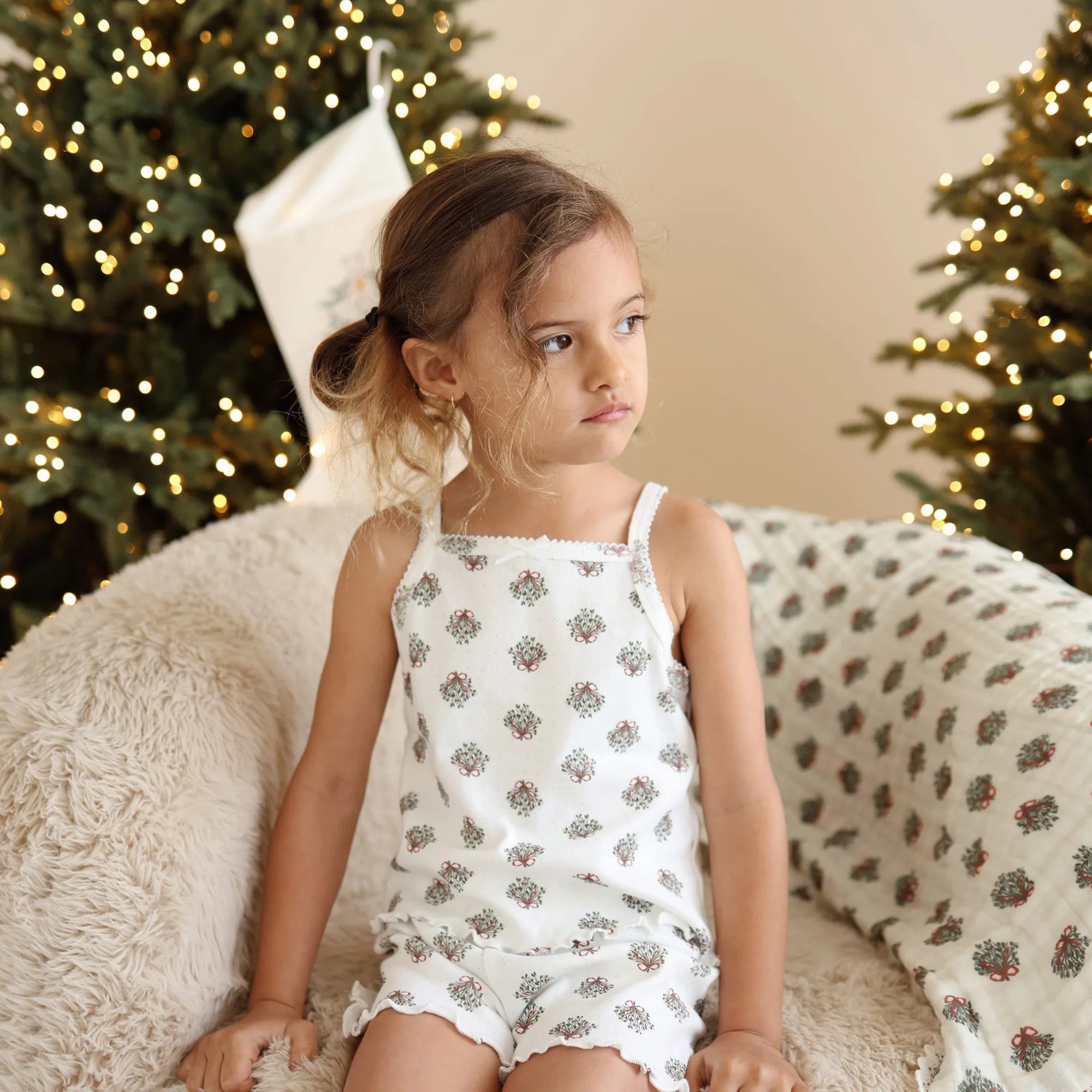 Girl in a wreath print singlet and shorts pyjama set beside a matching wreath print muslin wrap