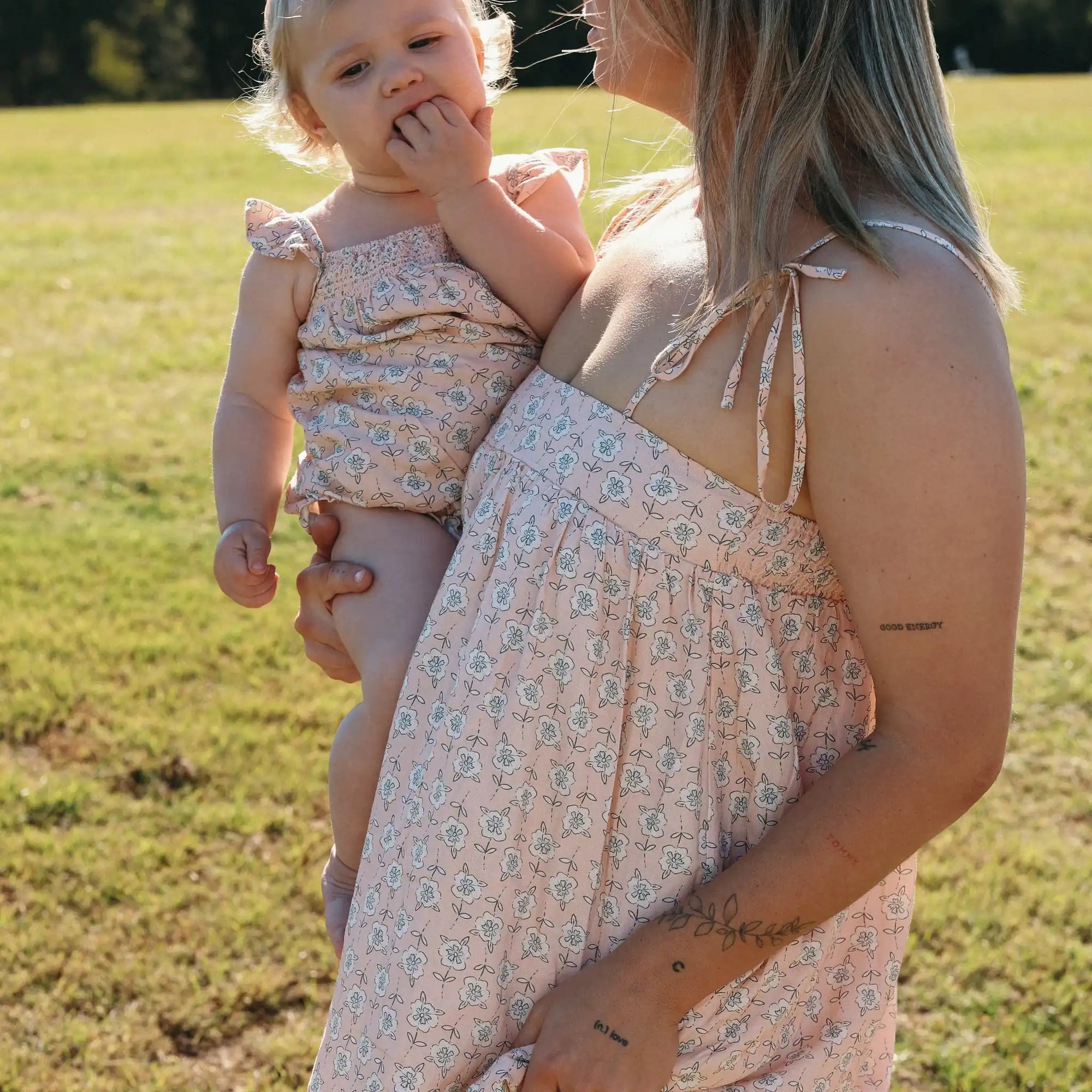 Mum in a floral print maxi dress holding a baby in a matching floral shirred romper